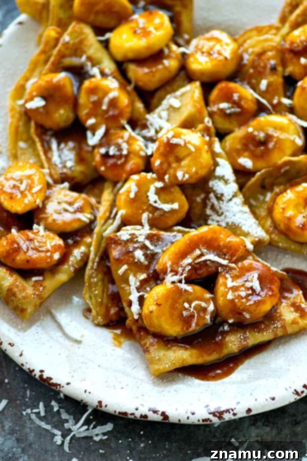 Golden Coconut Crepes with Sticky Banana Caramel 3 A stack of golden brown coconut crepes arranged neatly on a plate, ready to be topped with sweet caramelized banana sauce and other delicious garnishes for a memorable brunch