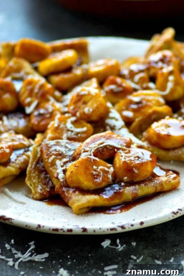 Golden Coconut Crepes with Sticky Banana Caramel 4 Close-up shot of a perfectly folded coconut crepe, revealing its tender texture, lightly browned edges, hinting at the delightful coconut flavor within, ready for the sauce