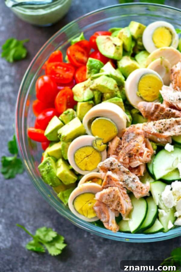 A loaded, flavorful Cobb Salad featuring grilled salmon and a vibrant cilantro lime ranch dressing.