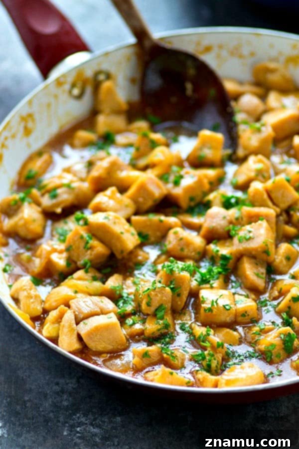 Close-up of tender chicken pieces perfectly coated in a vibrant, sweet, and tangy orange sauce.