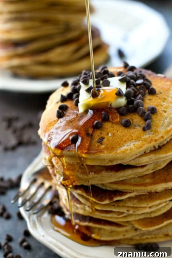 Decadent Almond Butter Chocolate Chip Flapjacks 4 A stack of golden brown almond butter chocolate chip pancakes, generously drizzled with maple syrup.