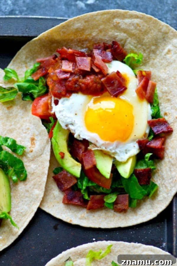 Crispy BLT Tostadas with Fried Egg and Fresh Avocado 4 A bird's eye view of a loaded breakfast tostada with a sunny-side-up egg, avocado slices, and bacon bits.