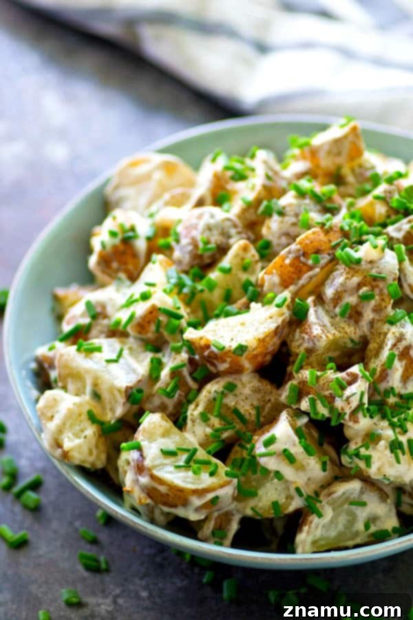 Elevated Roasted Potato Salad with Zesty Chive Ranch 5 Scooping generous portions of the delicious roasted potato salad, ready to be served at any gathering.