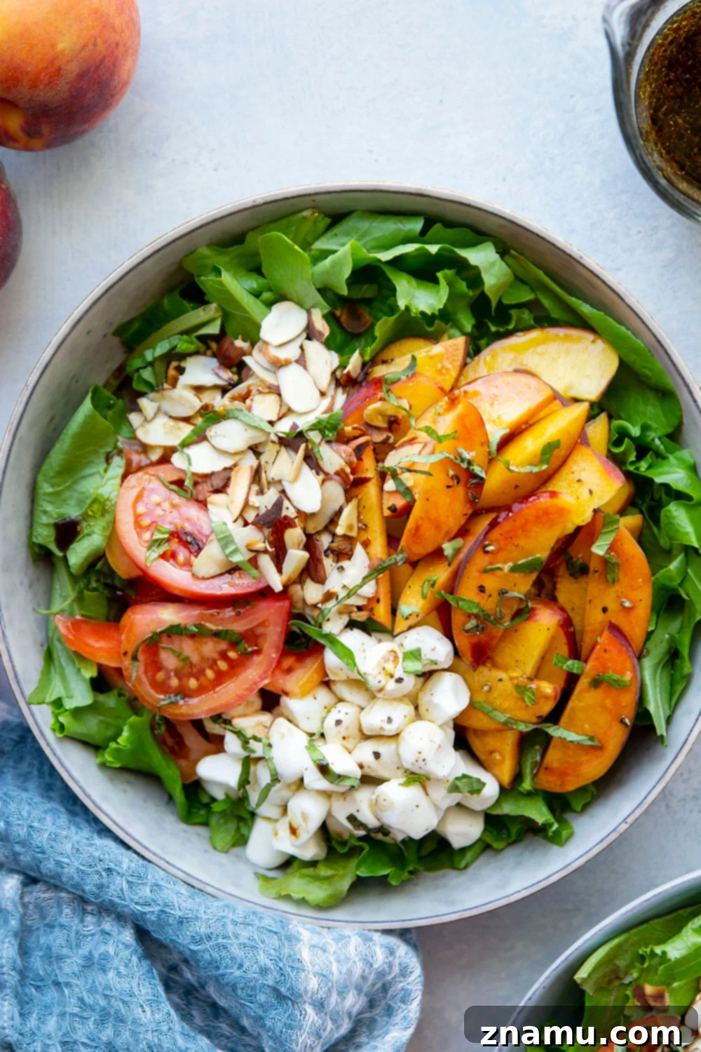 Sun-Drenched Peach Caprese 6 A vibrant summer peach caprese salad served in a white bowl, with basil leaves, mozzarella, and peaches visible, ready to be enjoyed.