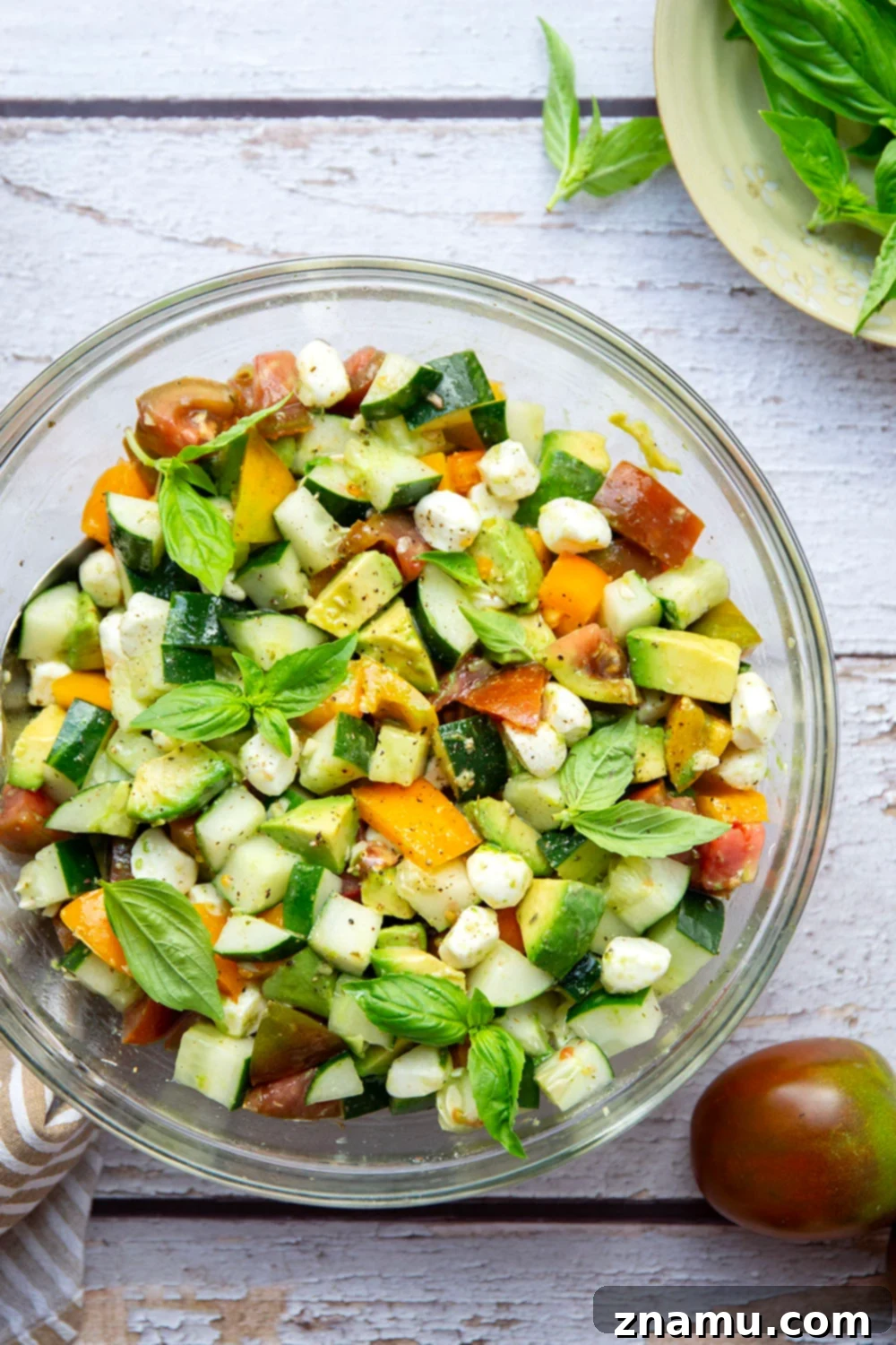 Classic Italian Tomato Cucumber Salad 2 A beautifully presented Italian Tomato Cucumber Salad, featuring fresh tomatoes, creamy avocados, crisp cucumbers, and soft mozzarella pearls, generously tossed in a flavorful homemade Italian vinaigrette.