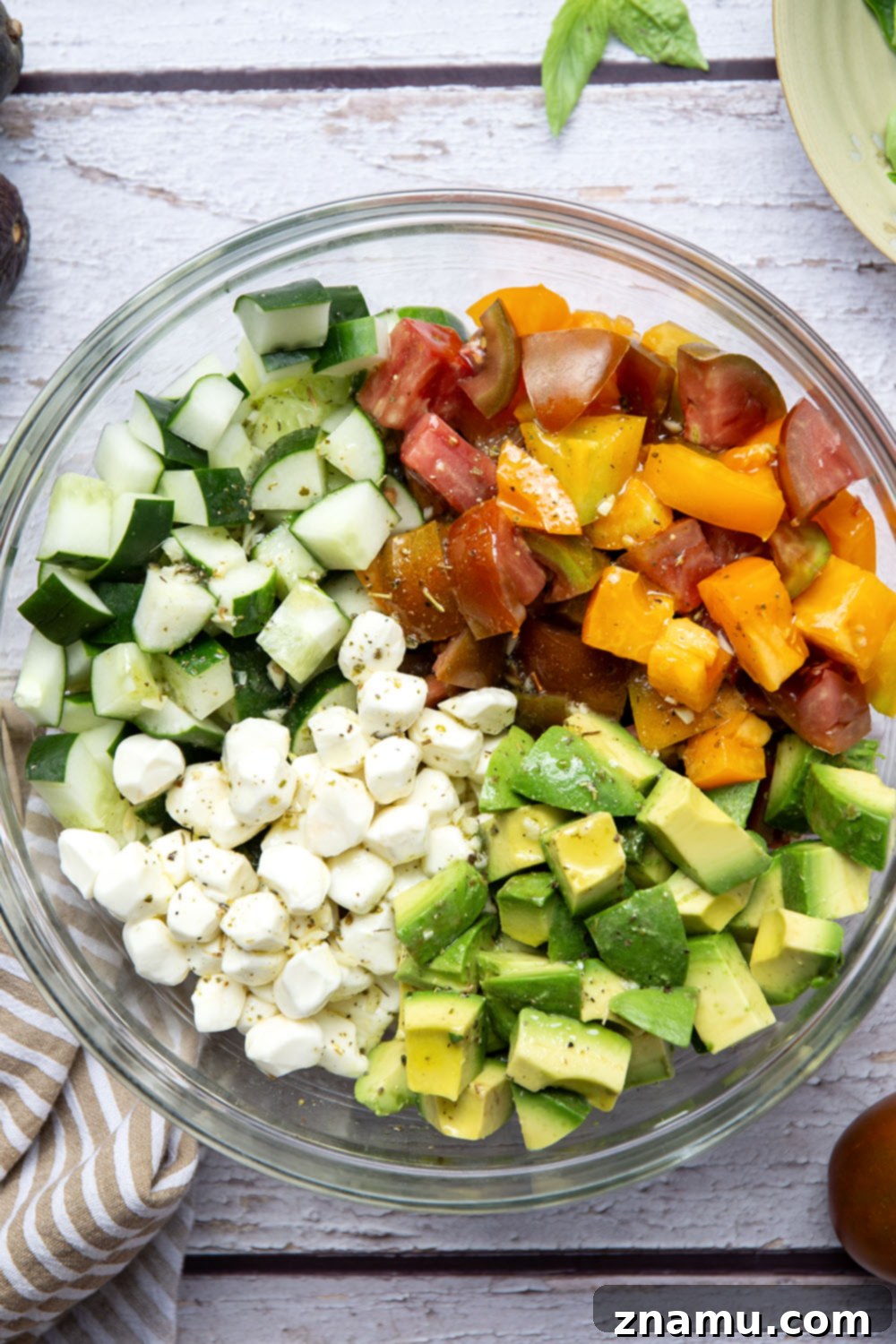 Classic Italian Tomato Cucumber Salad 3 Close-up shot of the fresh ingredients in the Italian Tomato Cucumber Salad, showcasing the vibrant colors and appealing textures of tomatoes, avocados, cucumbers, and mozzarella pearls.