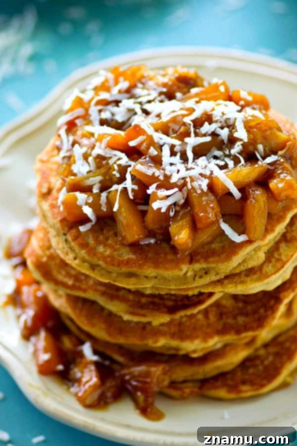 Coconut Cloud Pancakes with Zesty Orange-Pineapple Compote 3 Close-up of a perfectly golden-brown coconut pancake, ready to be topped with compote.