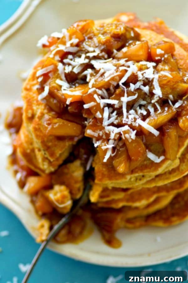 Coconut Cloud Pancakes with Zesty Orange-Pineapple Compote 4 Overhead shot of a breakfast table featuring a tall stack of coconut pancakes, fresh compote, and shredded coconut.