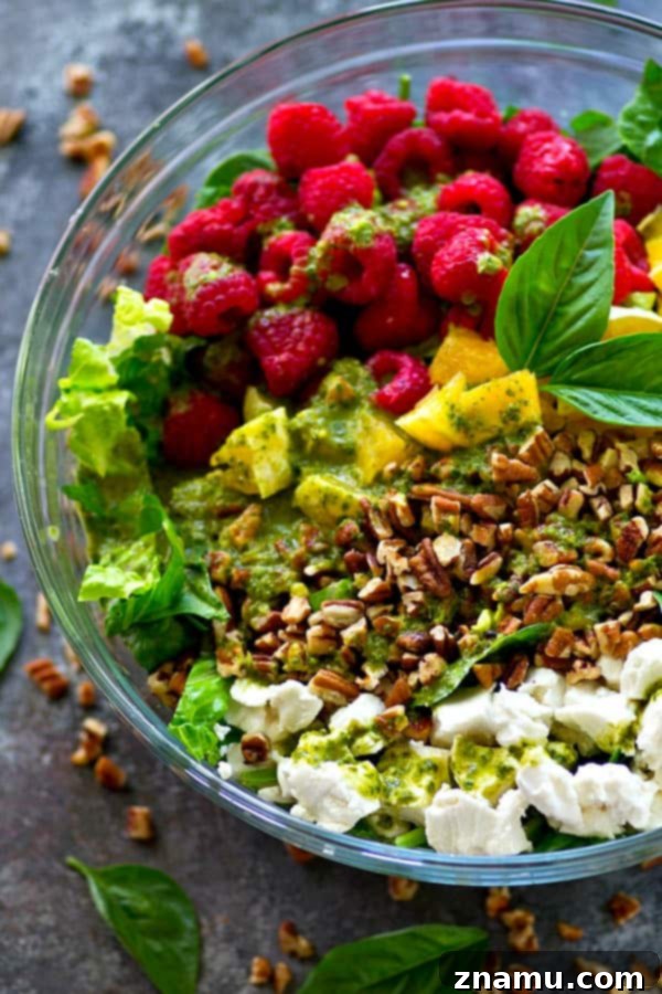A vibrant Raspberry Pecan Goat Cheese Salad with fresh basil vinaigrette, artfully arranged in a bowl.