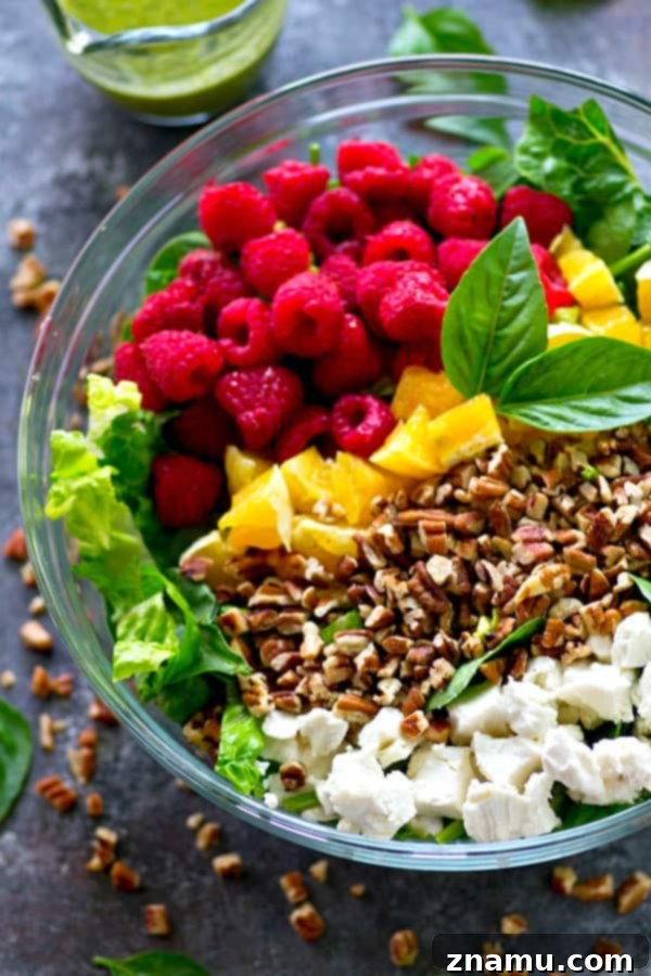 Close-up of the Raspberry Pecan Goat Cheese Salad, showcasing fresh raspberries, crumbled goat cheese, and toasted pecans on a bed of greens.