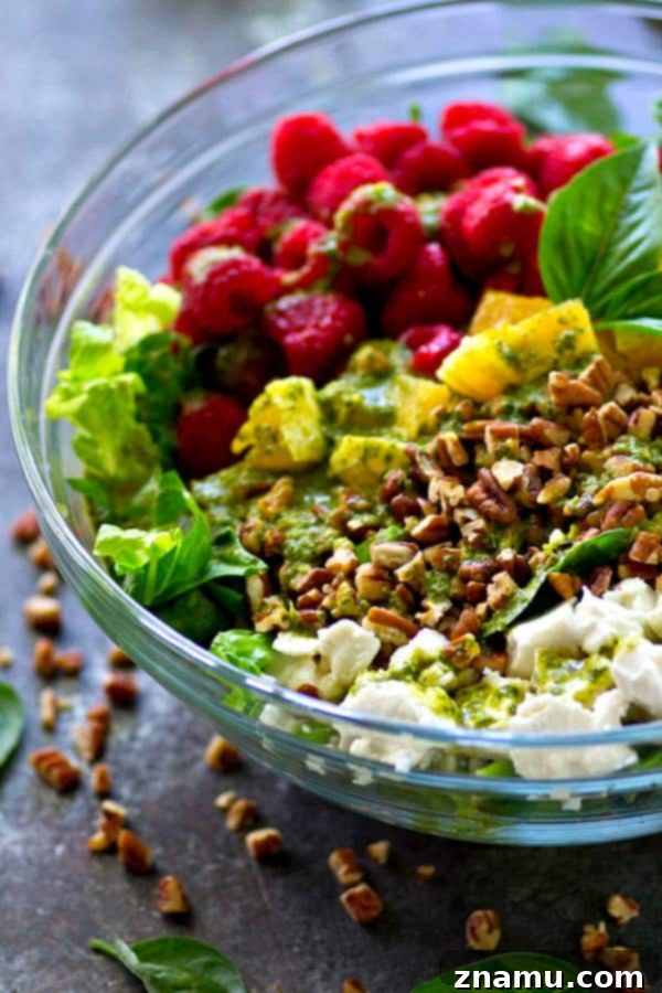 A top-down view of the colorful Raspberry Pecan Goat Cheese Salad, drizzled generously with homemade basil vinaigrette.