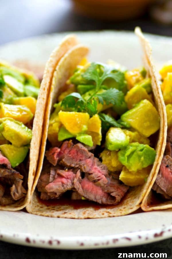 Marinated flank steak grilling to perfection, ready for slicing into tender taco filling.