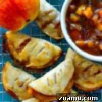 Sweet Summer Peach Pockets 8 A charming close-up of a mini peach hand pie, highlighting its flaky crust and the rich, golden peach filling.