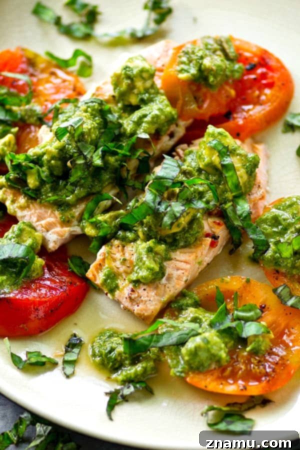 Grilled Salmon with a Medley of Heirloom Tomatoes and Zesty Avocado Chimichurri 3 Close-up of grilled salmon and heirloom tomatoes with avocado chimichurri sauce, showcasing fresh ingredients.
