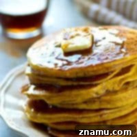 A stack of golden pumpkin chai spice pancakes with syrup and butter