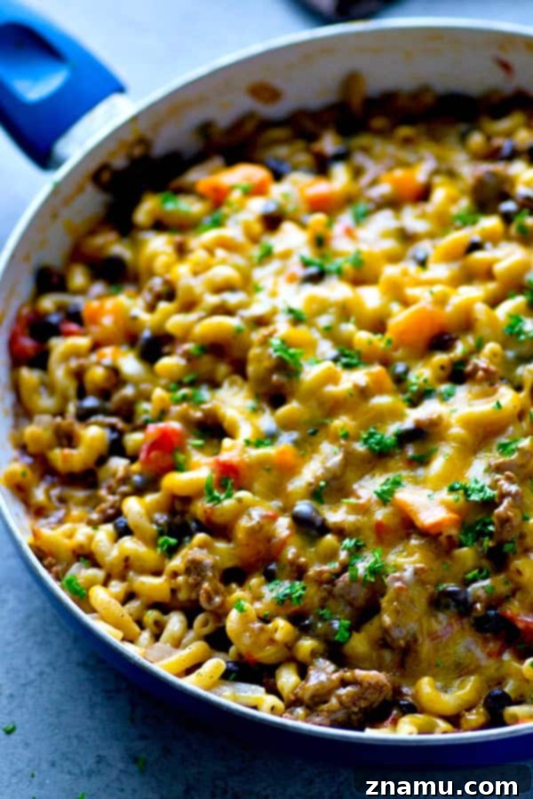 Lean Skillet Beef Chili Mac n Cheese 4 A scoop of Lighter One-Pot Beef Chili Mac and Cheese being lifted, with strings of melted cheddar cheese stretching enticingly.