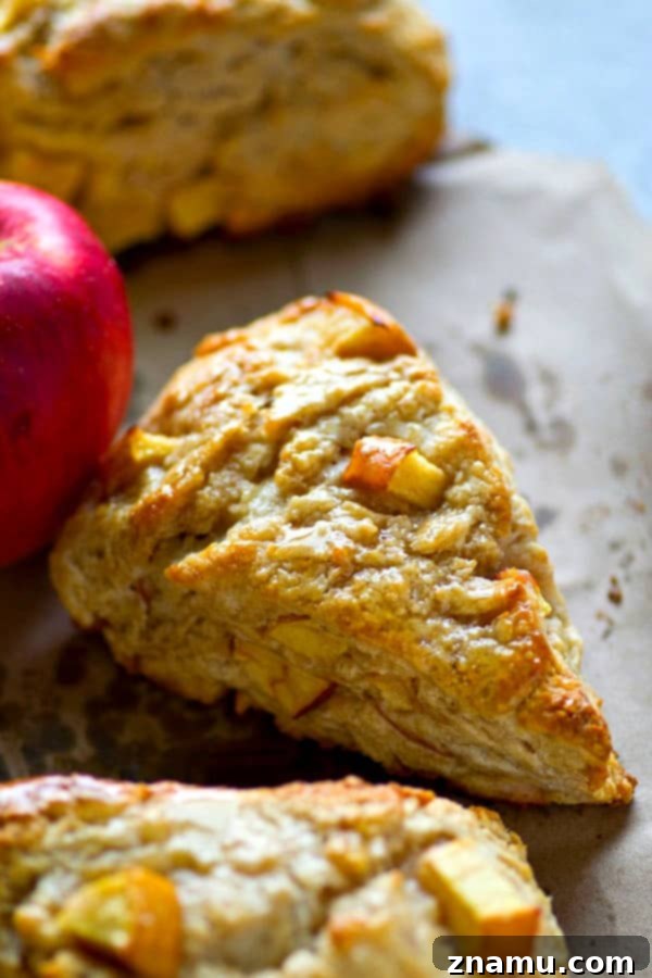 Maple Apple Cream Cheese Scones 4 Golden-brown Maple Cream Cheese Apple Scones arranged on a cooling rack, steam gently rising, ready to be enjoyed as a delightful fall treat.