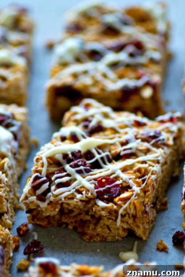 Heavenly White Chocolate Cranberry Granola Bars 4 A stack of freshly baked White Chocolate Cranberry Bliss Granola Bars, highlighting the generous white chocolate topping and vibrant red cranberries.