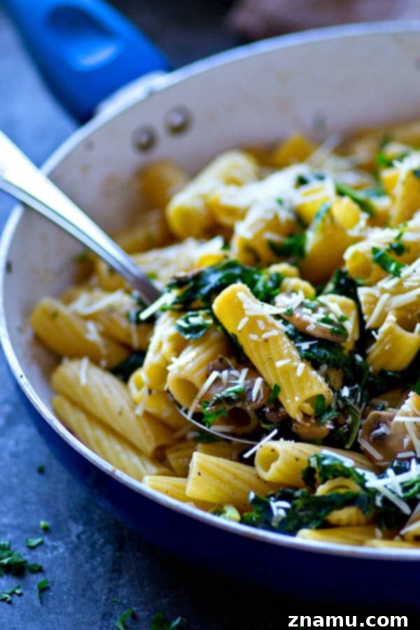 Browned Butter Rigatoni with Caramelized Mushrooms and Kale 4 A serving of browned butter rigatoni with caramelized mushrooms, kale, and a generous sprinkle of grated Parmesan cheese, ready to be savored.