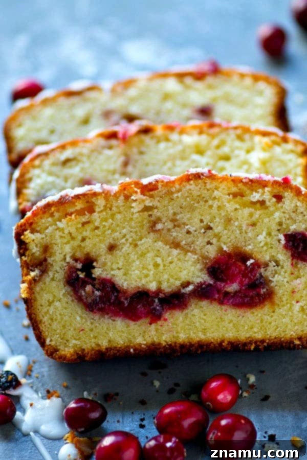 Almond Pound Cake with Cranberry Swirl 5 A delicious cranberry swirl almond pound cake, generously drizzled with white glaze, ready to be served on a festive table.