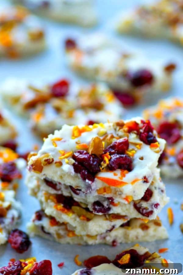 Artisan White Chocolate Bark with Bright Orange, Tart Cranberry, and Toasted Pecans 4 Beautifully arranged White Chocolate Pecan Orange Cranberry Bark on parchment paper