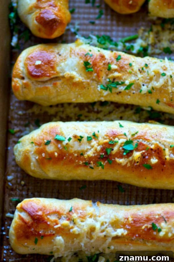 Stack of freshly baked Garlic Butter Parmesan Soft Pretzel Breadsticks on a cooling rack
