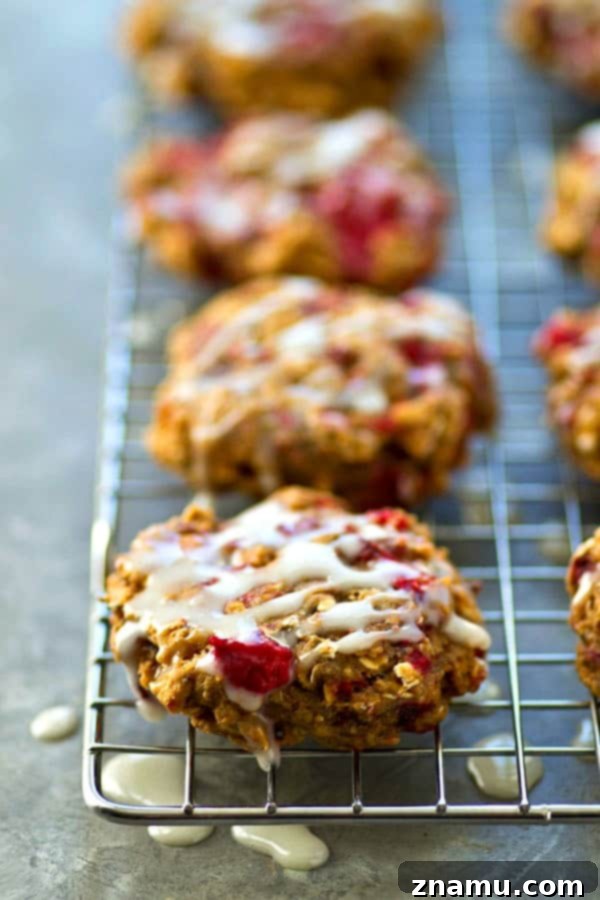 Dreamy Raspberry Cheesecake Breakfast Cookies 3 Close-up of a stack of Raspberry Cheesecake Breakfast Cookies, showing the vibrant raspberries and smooth glaze.