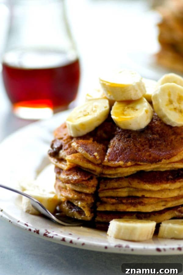 An appetizing close-up of a stack of cinnamon crunch banana buttermilk pancakes with syrup