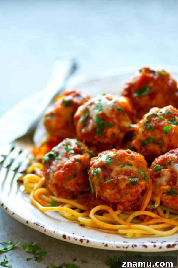 Cheesy Instant Pot Chicken Parmesan Meatballs 4 A close-up of a serving of Instant Pot Chicken Parmesan Meatballs with rich marinara sauce and fresh basil on top.