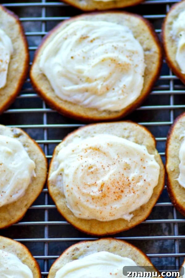 Irresistible Banana Bread Muffin Tops with Cream Cheese Frosting 3 Two banana bread muffin tops on a white plate, one frosted, highlighting texture