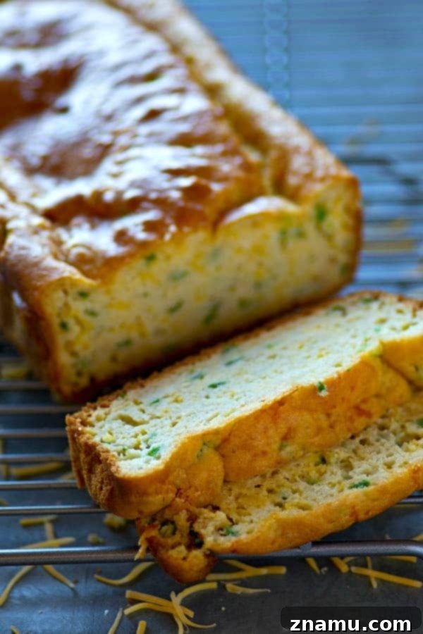 Zesty Cheddar Jalapeno Quick Loaf 4 Close-up of a warm slice of Cheesy Jalapeño Cheddar Quick Bread, showing the molten cheddar and vibrant green jalapeño bits embedded in the soft bread.