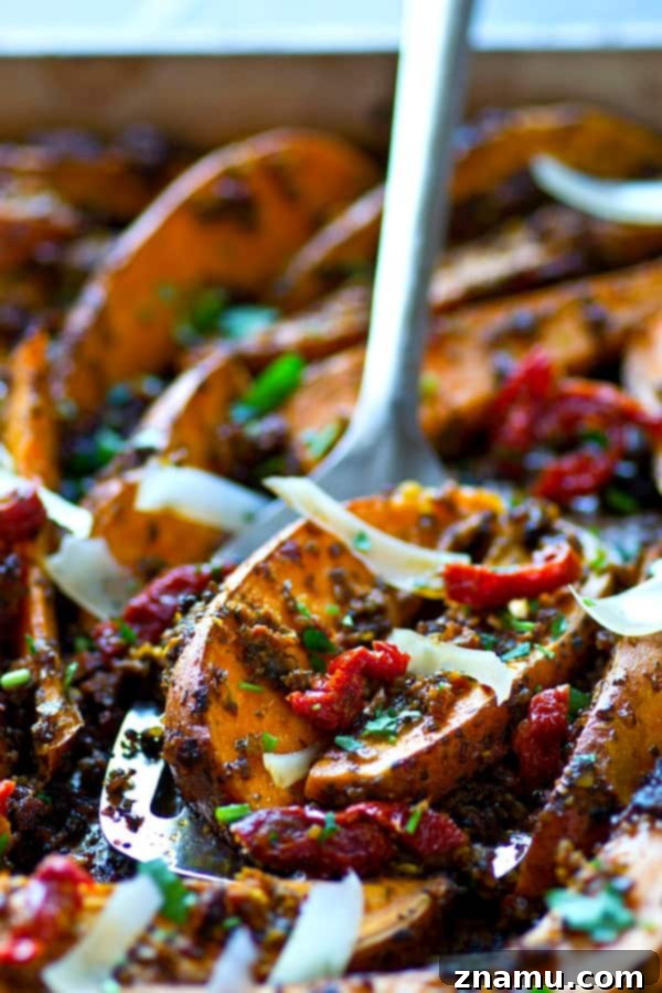 Tangy Pesto Roasted Sweet Potato Wedges 4 Three perfectly roasted sweet potato wedges, glistening with pesto and Parmesan, arranged on a rustic wooden surface with sun-dried tomatoes.