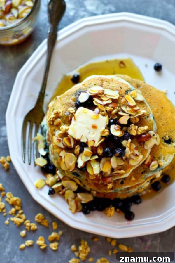 Golden Blueberry Granola Stacks, Drizzled with Almond Syrup 3 A stack of blueberry granola pancakes with fresh blueberries and almond syrup