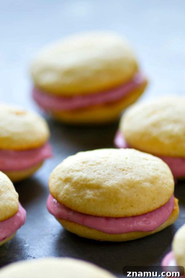 Vanilla Raspberry Cheesecake Whoopie Dreams 5 A close-up of a halved vanilla whoopie pie showing the generous raspberry cream cheese filling