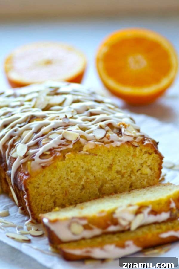 Zesty Orange Almond Glaze Loaf 4 Overhead view of a whole loaf of Glazed Almond Orange Quick Bread, showing the generous layer of glaze and a sprinkle of almonds.