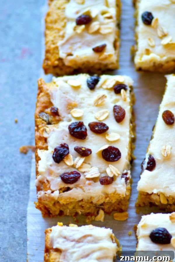 Frosted Oatmeal Raisin Morning Bars 5 A hand reaching for a frosted oatmeal raisin breakfast bar, showcasing its inviting texture