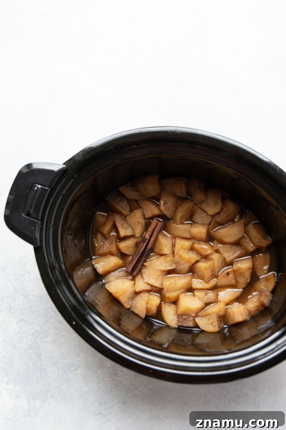 Homemade Slow Cooker Apple Butter 3 A styled shot of a serving spoon scooping smooth slow cooker apple butter from a small bowl, showcasing its rich, spreadable consistency.