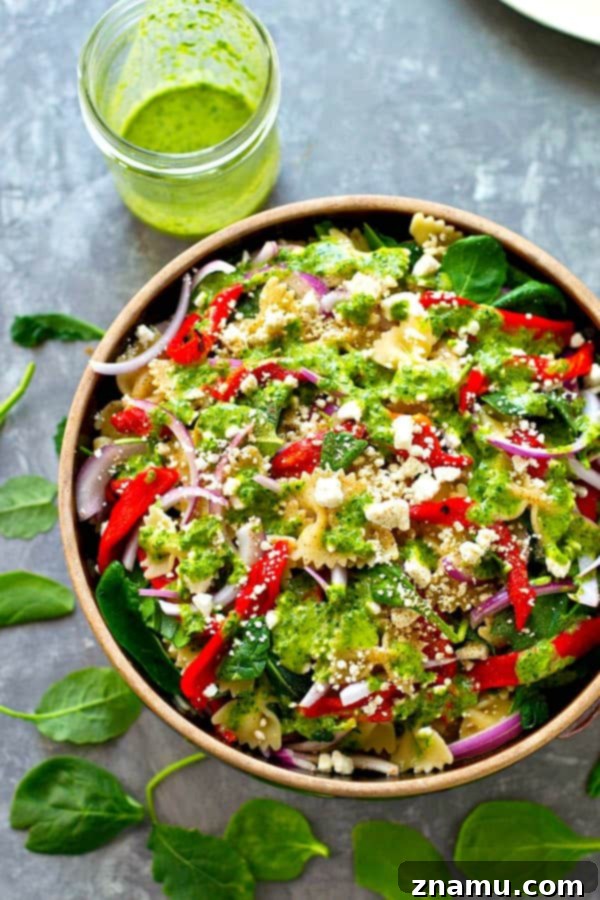 Mediterranean Roasted Red Pepper Feta Pasta Salad with Basil Vinaigrette 3 Close-up of a serving of Roasted Red Pepper Feta Pasta Salad, showing the bow-tie pasta, red peppers, and crumbled feta