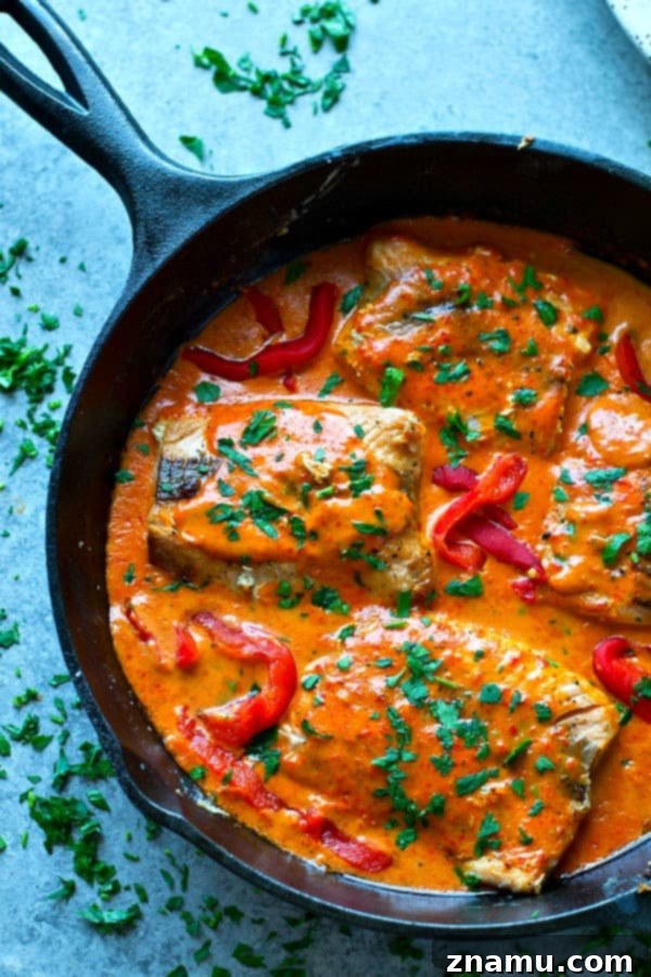 Vibrant Red Pepper Alfredo Salmon 3 Pan-Seared Salmon with Roasted Red Pepper Alfredo Sauce on a plate with fresh parsley