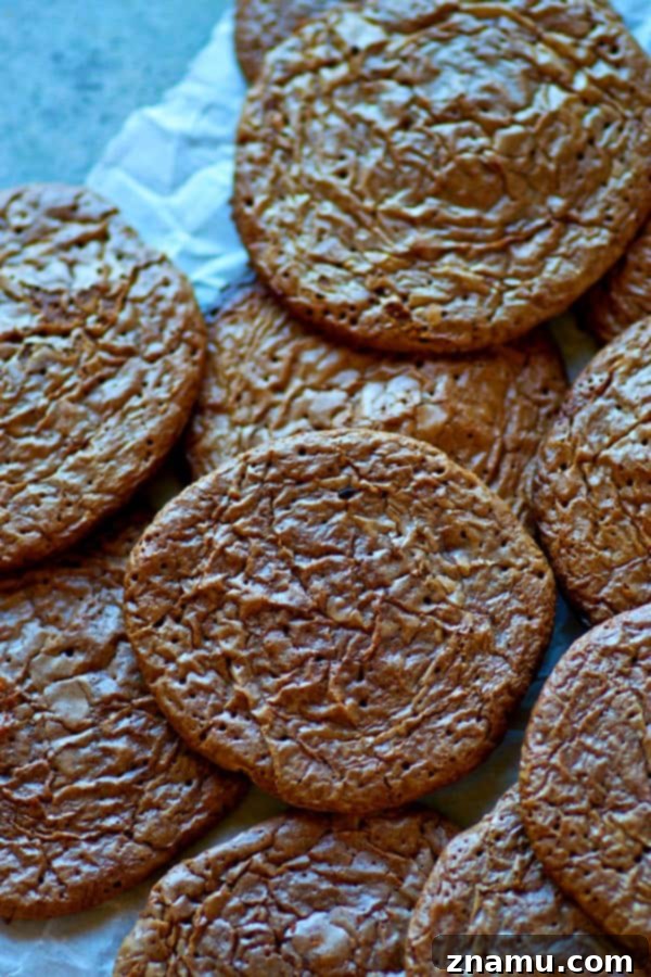 Fudgy Crinkle Brownie Cookies 5 Hand reaching for a warm, freshly baked brownie cookie from a baking sheet