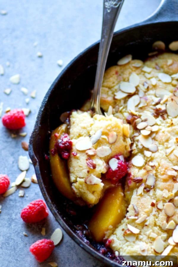 Delicious Skillet Raspberry Almond Peach Cobbler with fresh fruit and almond topping, baked in a cast iron pan