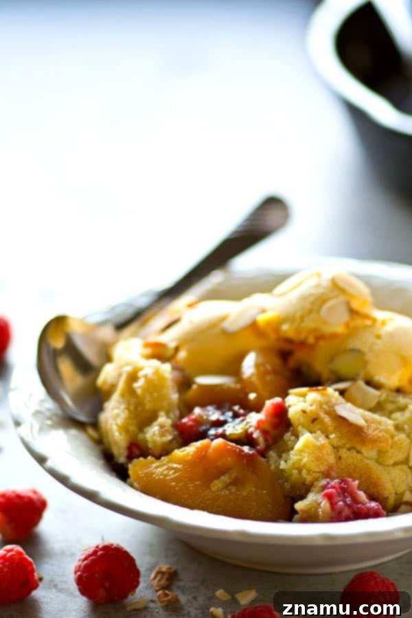 A close-up of the gooey fruit filling and crisp almond topping of the Skillet Raspberry Almond Peach Cobbler