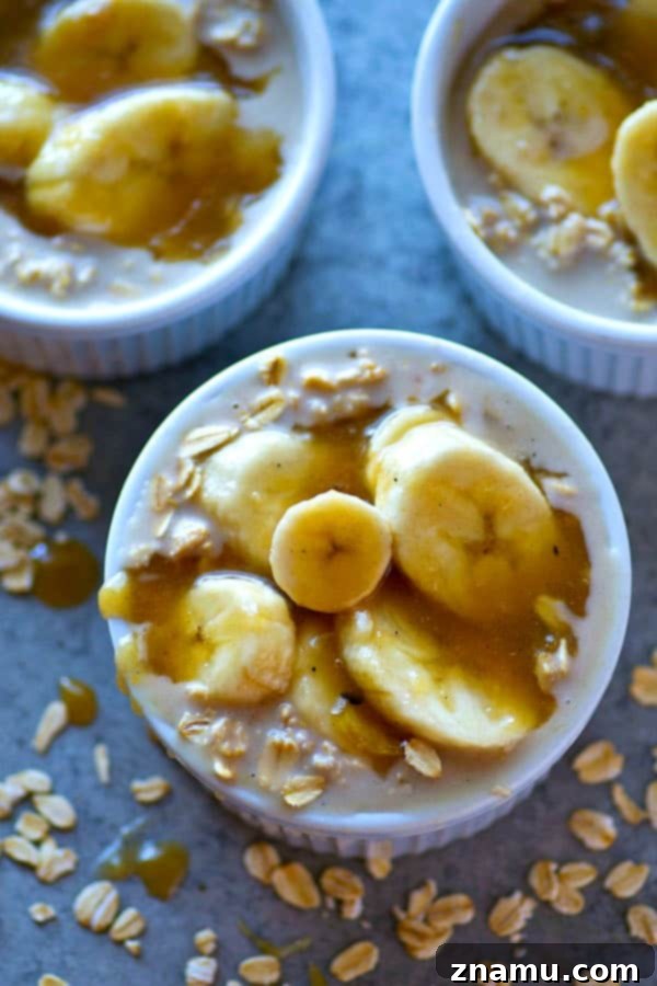 Overhead shot of two bowls of Caramel Macchiato Banana Overnight Oats, garnished with extra caramel drizzle and a small spoon on a rustic surface.