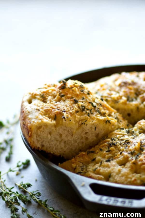 Effortless Overnight Parmesan Herb Focaccia 4 A generous slice of warm No-Knead Parmesan Herb Focaccia, highlighting its airy, open crumb and fragrant herb-infused olive oil.