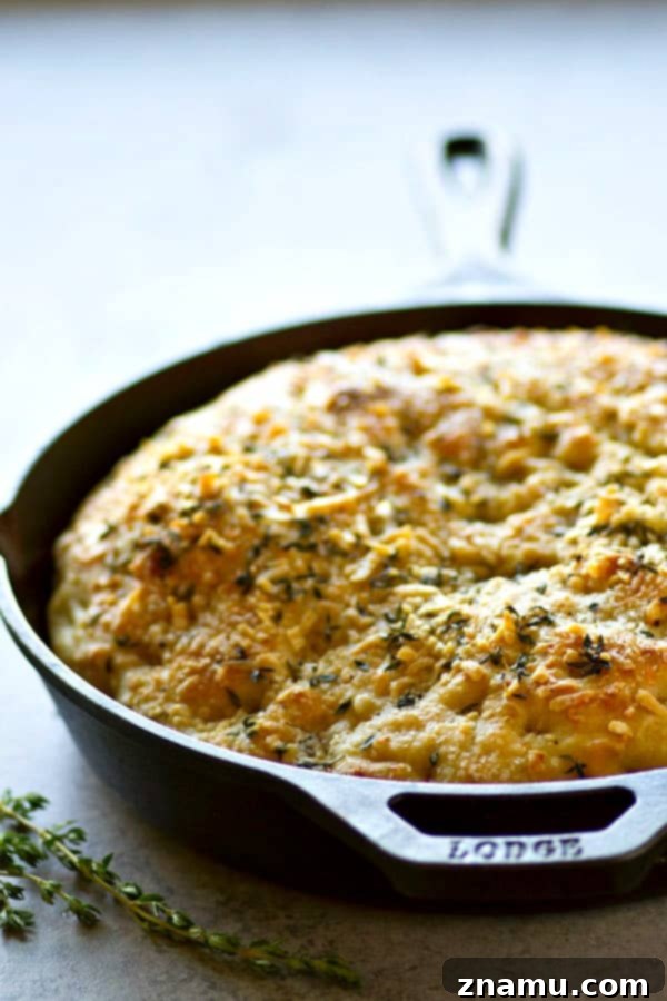 Effortless Overnight Parmesan Herb Focaccia 5 A close-up of freshly baked No-Knead Parmesan Herb Focaccia, cooling slightly in a cast iron skillet, ready to be sliced and enjoyed.