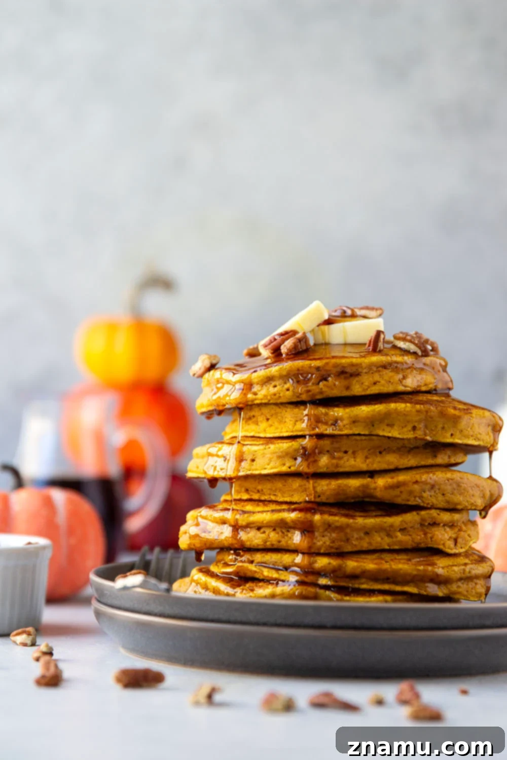 Warm Spiced Pumpkin Stacks 2 Fluffy pumpkin spice pancakes generously drizzled with warm maple syrup and sprinkled with toasted pecans, perfect for a cozy fall breakfast.