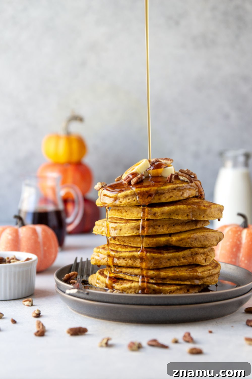 Warm Spiced Pumpkin Stacks 4 A stack of golden pumpkin spice pancakes on a white plate, ready to be served, highlighting their soft texture.