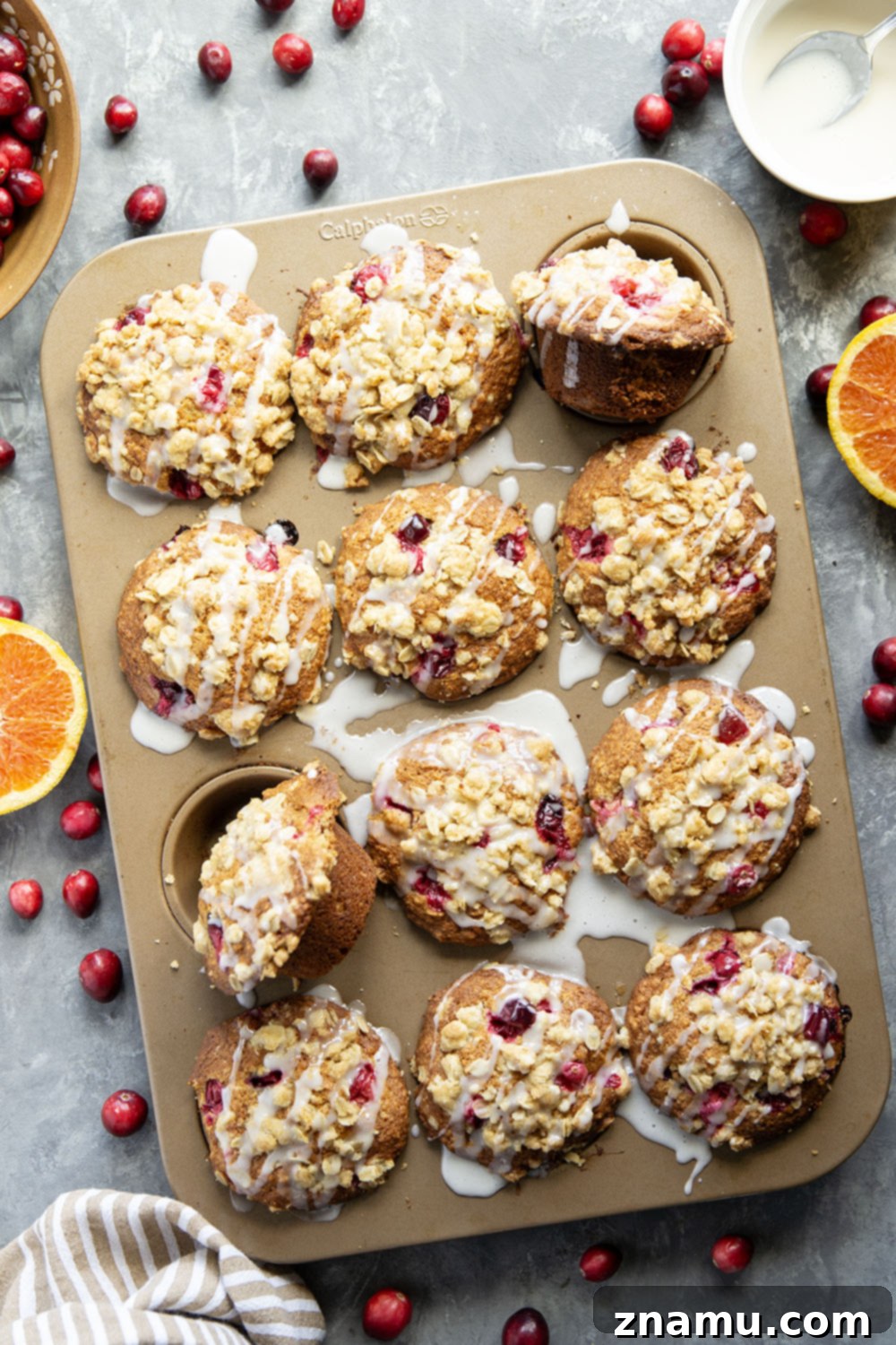 Wholesome Cranberry Oat Muffins 4 Close-up of a single cranberry oatmeal muffin, revealing its moist interior, scattered cranberries, and the glistening orange glaze on top.