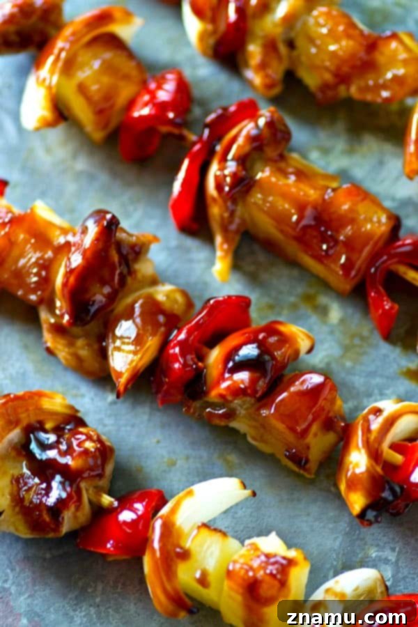 Several grilled pineapple sweet pepper chicken kebabs served on a platter, ready to eat.