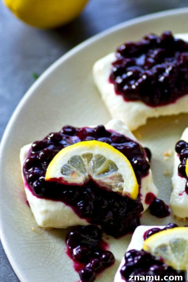 Refreshing No-Bake Blueberry Lemon Cheesecake Bars 3 A close-up of a single no-bake blueberry lemon cheesecake bar, showcasing the thick creamy lemon layer and generous blueberry sauce on a firm graham cracker base.